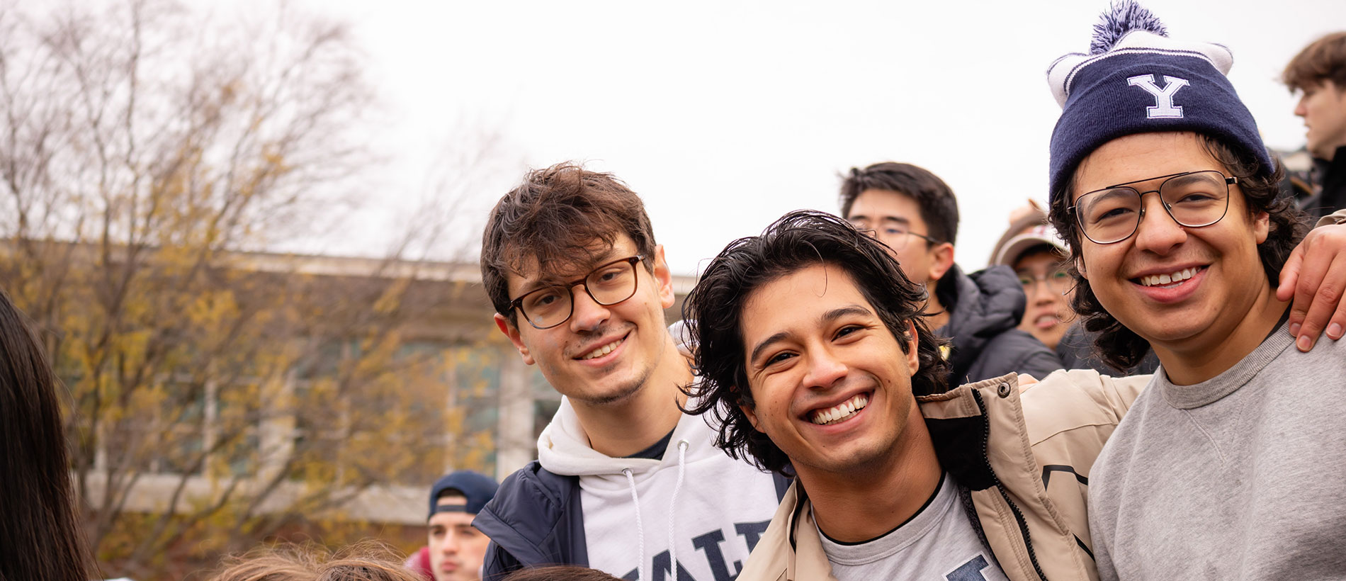 Young men wearing Yale hats and smiling at the camera