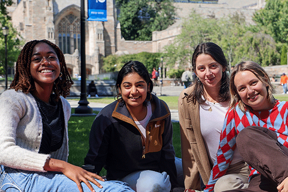 Young women sitting in the grass and smiling at the camera